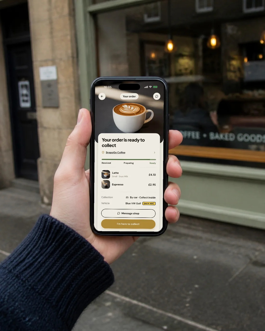 A customer outside a café holding a phone showing the SnappGo screen: Your order is ready to collect