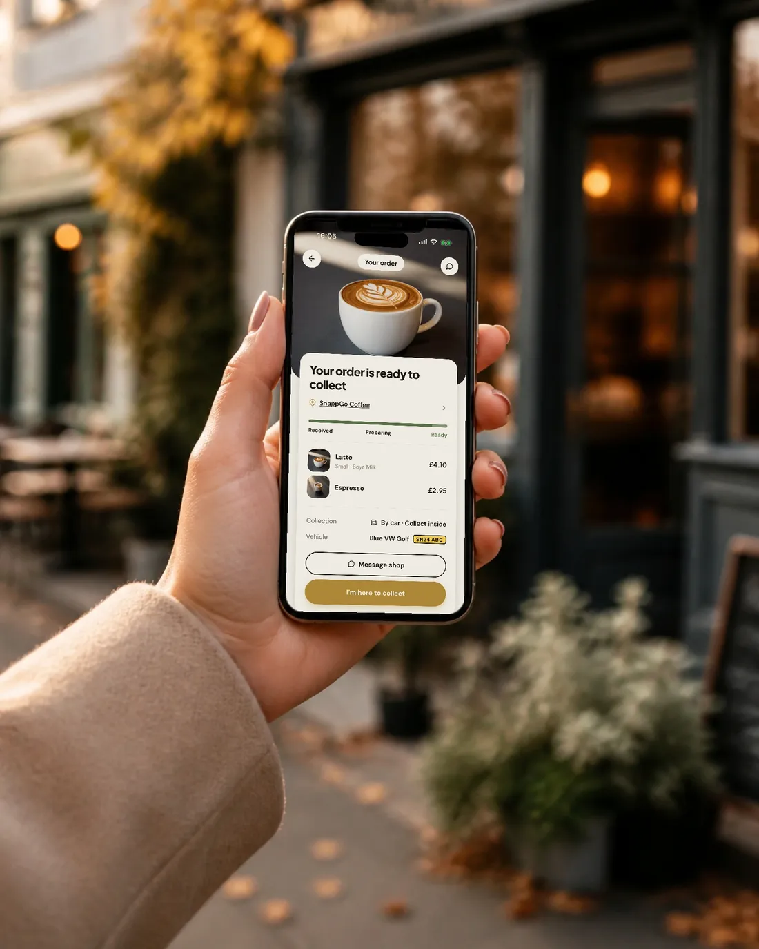 A customer outside a café holding a phone showing the SnappGo screen: Your order is ready to collect